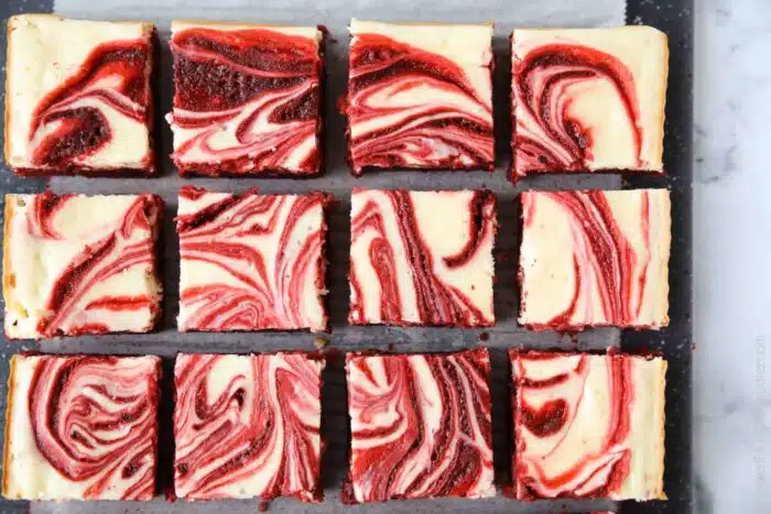 Swirled red velvet cheesecake brownies cut into squares.