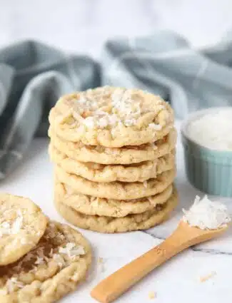 A stack of soft and chewy coconut cookies with extra shredded coconut on top.