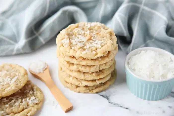 A stack of soft and chewy coconut cookies with extra shredded coconut on top.