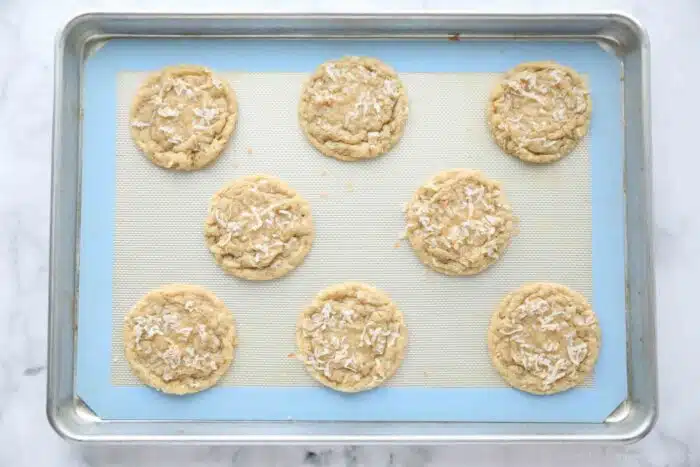 Baked coconut cookies on a sheet tray, fresh from the oven.