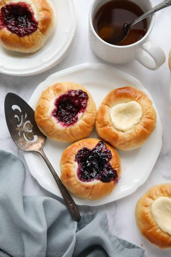 Raspberry, blueberry, and cream cheese kolaches on a plate.