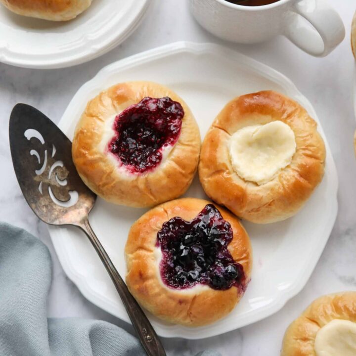 Raspberry, blueberry, and cream cheese kolaches on a plate.