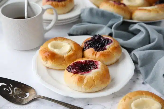 Raspberry, blueberry, and cream cheese kolaches on a plate.