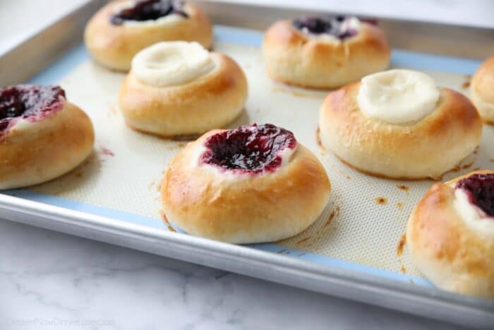 Baked fruit and cream cheese kolaches on a pan.
