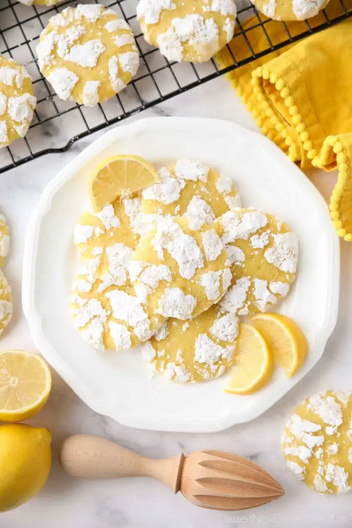 Lemon crinkle cookies on a plate with lemon wedges.