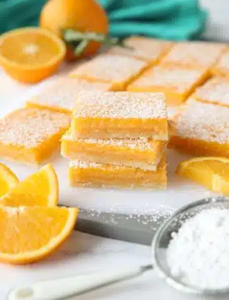 A stack of Orange Bars with powdered sugar dusted on top. (Like lemon bars, but with oranges.)