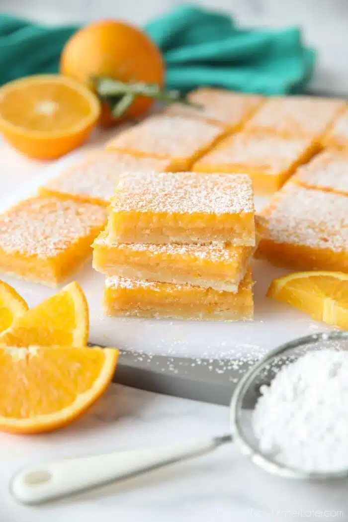 A stack of Orange Bars with powdered sugar dusted on top. (Like lemon bars, but with oranges.)