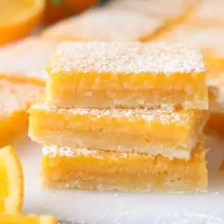 Close-up of a stack of orange bars with powdered sugar dusted on top.
