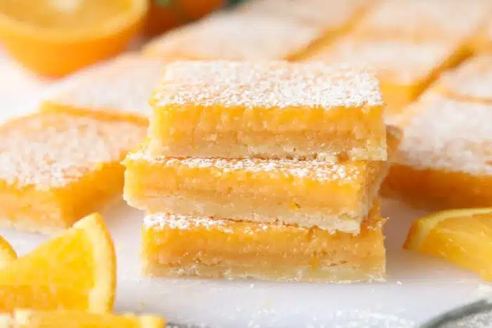 Close-up of a stack of orange bars with powdered sugar dusted on top.