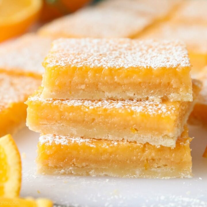 Close-up of a stack of orange bars with powdered sugar dusted on top.