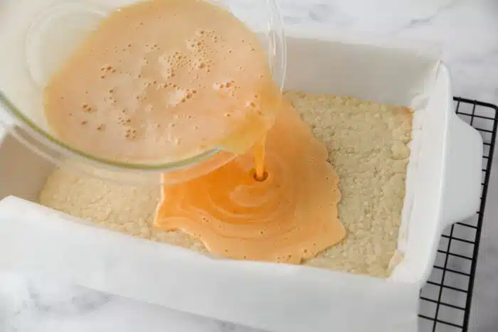 Pouring the orange custard filling onto the baked crust.