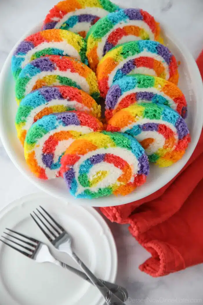 Slices of rainbow striped cake roll on a plate.