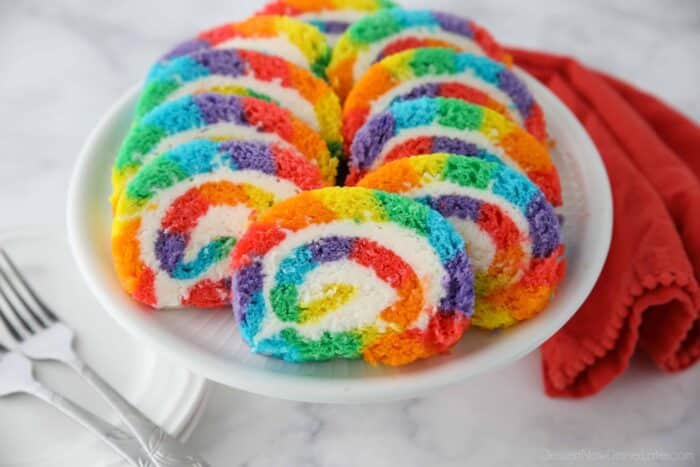 Slices of rainbow striped cake roll on a plate.