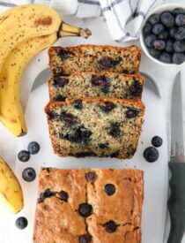 Blueberry banana bread with sour cream sliced on cutting board.