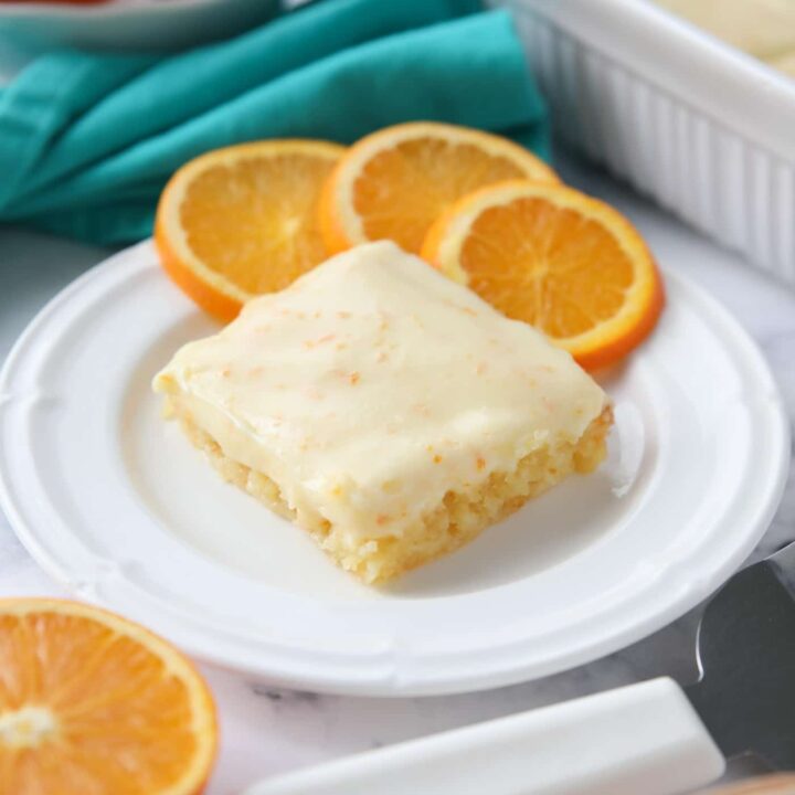 Orange Brownies on a plate with slices of oranges.