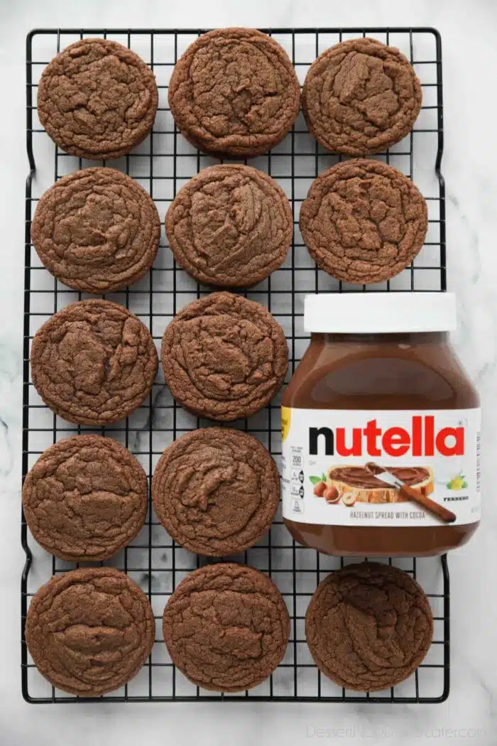 Nutella cookies on a wire cooling rack next to a jar of Nutella hazelnut spread with cocoa.