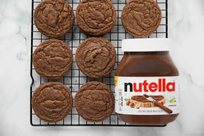 Jar of Nutella next to baked cookies on a wire cooling rack.