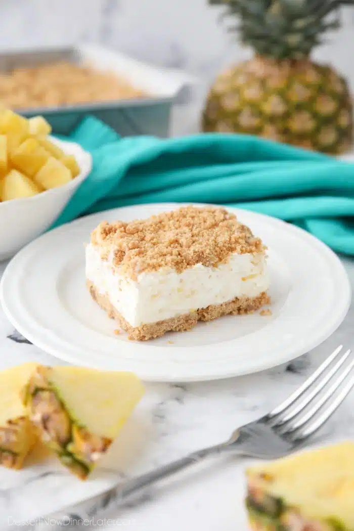 Side view of a slice of pineapple delight on a plate. A creamy pineapple dream dessert with buttery graham cracker crumbs.