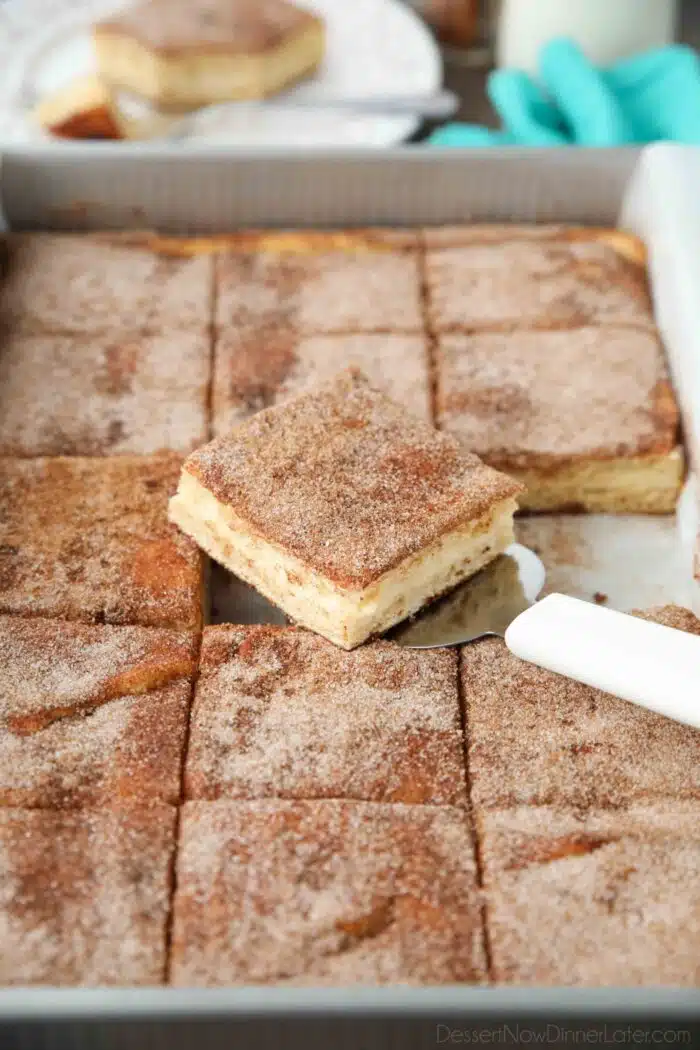 Spatula removing a piece of sopapilla cheesecake bars from a pan.