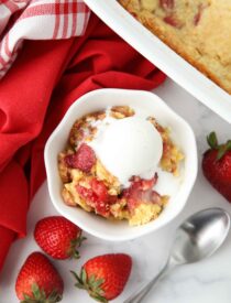 Strawberry dump cake made with fresh strawberries in a bowl with ice cream on top.