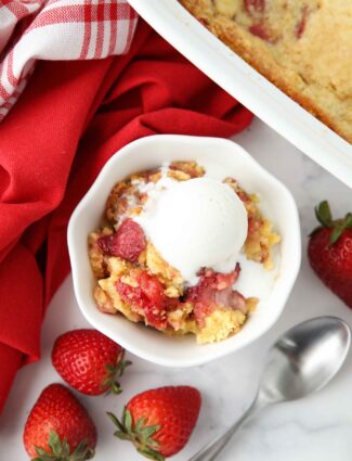 Strawberry dump cake made with fresh strawberries in a bowl with ice cream on top.