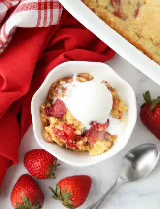 Strawberry dump cake made with fresh strawberries in a bowl with ice cream on top.