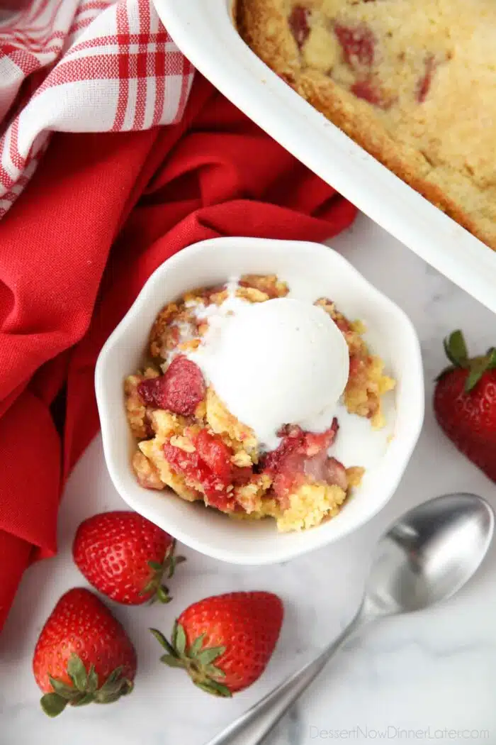 Strawberry dump cake made with fresh strawberries in a bowl with ice cream on top.