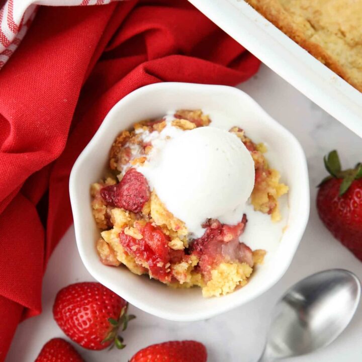 Strawberry dump cake made with fresh strawberries in a bowl with ice cream on top.