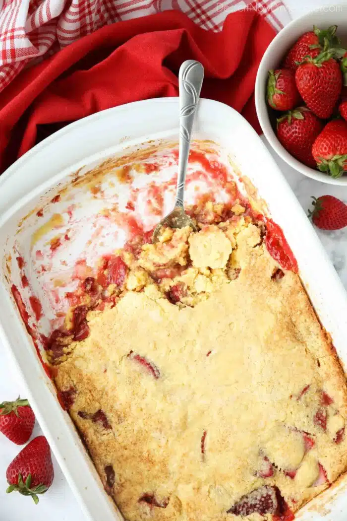 Pan of strawberry dump cake with spoon inside and some dessert removed.