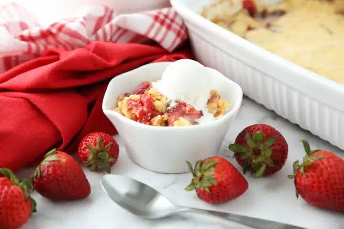Bowl of strawberry dump cake with ice cream on top.