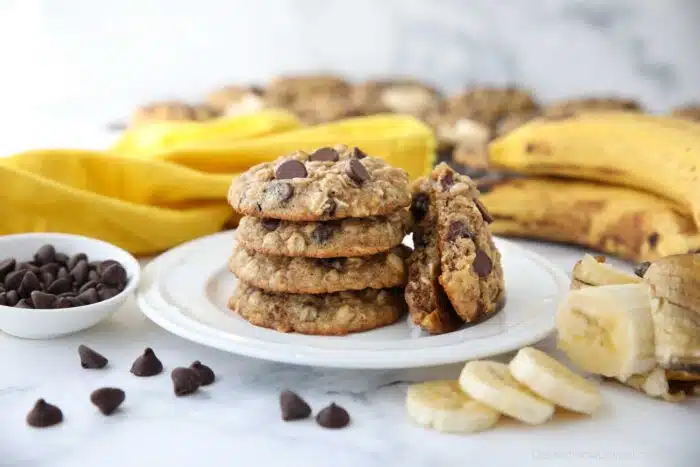 Stack of banana oatmeal chocolate chip cookies on a plate with one cookie broken in half.