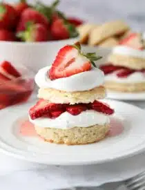 Stack of strawberry shortcake made with biscuits, whipped cream, and strawberries.