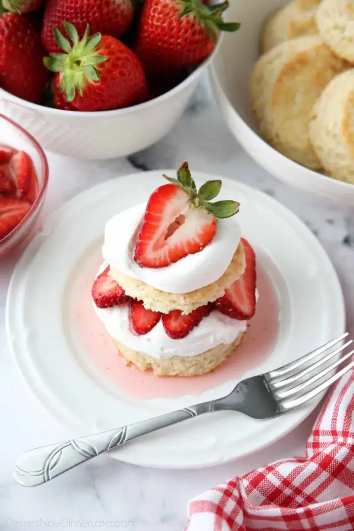 Top view of strawberry shortcake stack with biscuits, whipped cream, and strawberries.