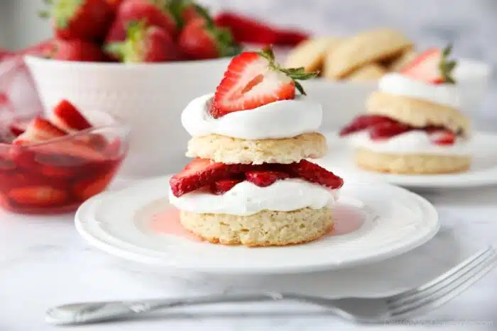 Stack of strawberry shortcake made with biscuits, whipped cream, and strawberries.