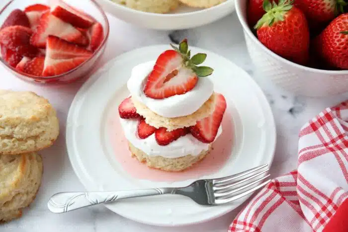Top view of strawberry shortcake stack with biscuits, whipped cream, and strawberries.