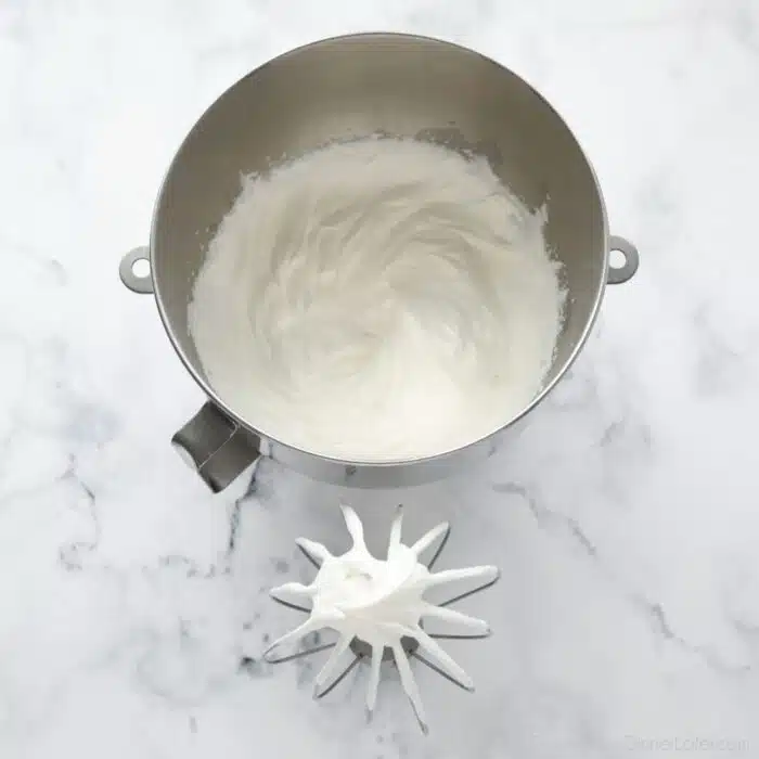 Whipped cream in a bowl with a whisk.