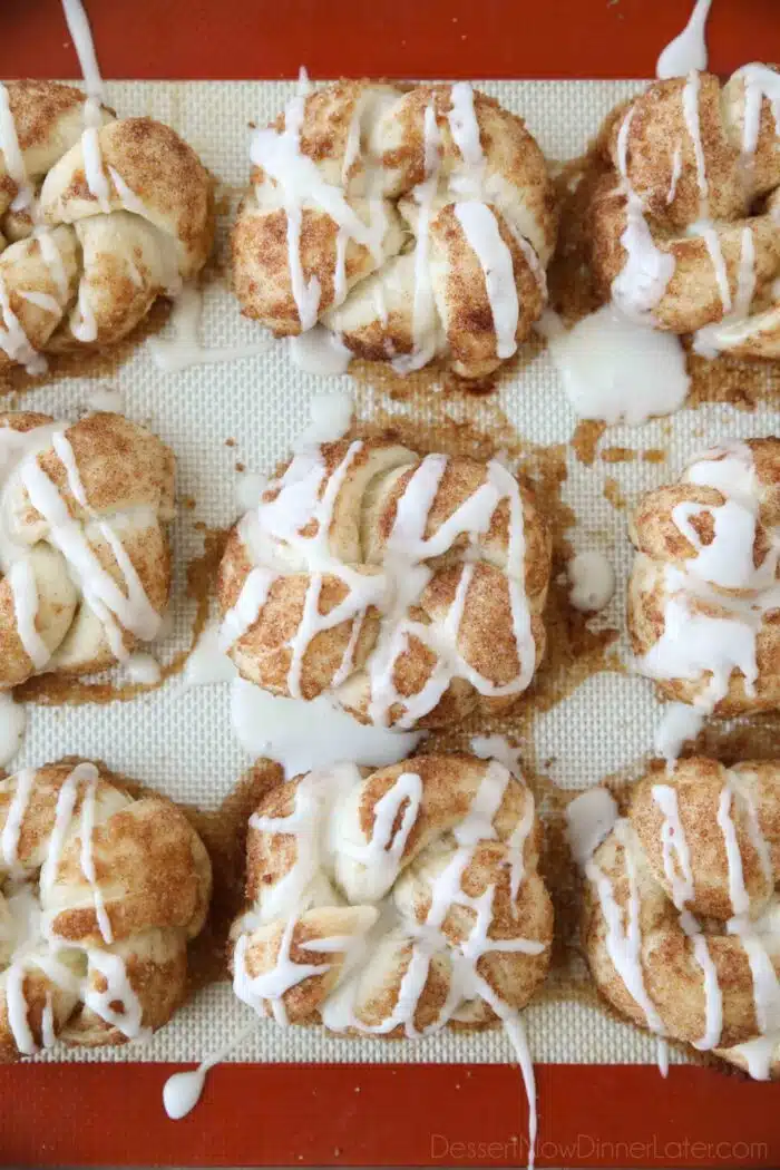 Icing drizzled over baked cinnamon roll knots.