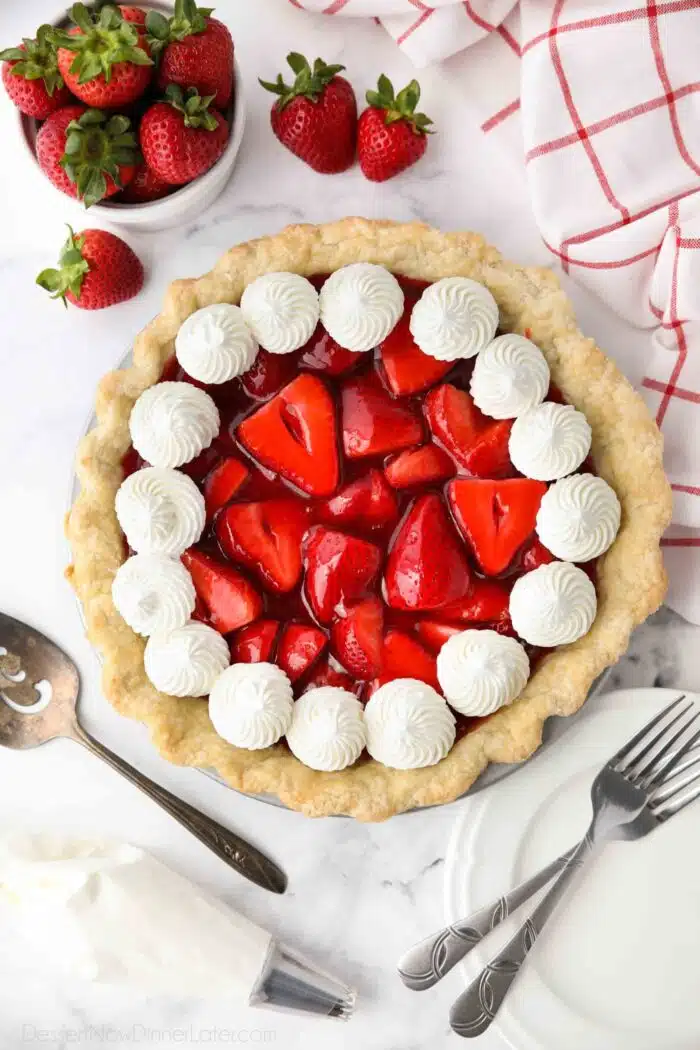 Top view of fresh strawberry pie with jello glaze and whipped cream.