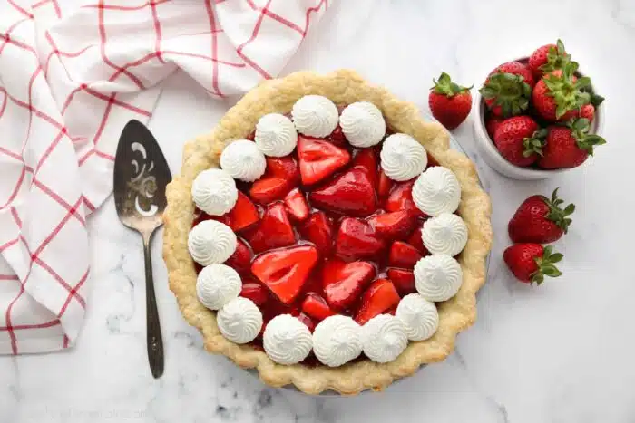 Top view of fresh strawberry pie with jello glaze and whipped cream.