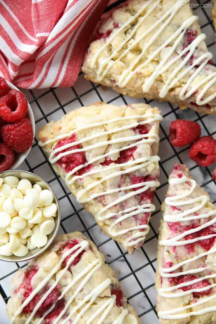 Close up of raspberry scones with white chocolate drizzled on top.