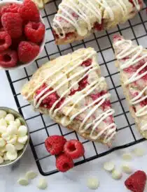 White chocolate raspberry scones on a wire cooling rack.