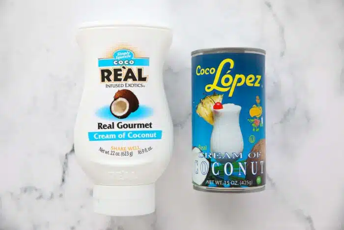 Two brands of cream of coconut. Coco Real in a bottle and Coco Lopez in a can.