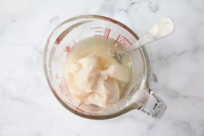 Separated Cream of Coconut from a can inside a glass measuring cup with a fork to stir it up.