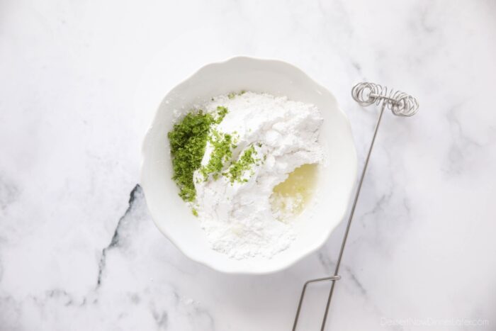 Lime glaze ingredients in a bowl with a whisk.