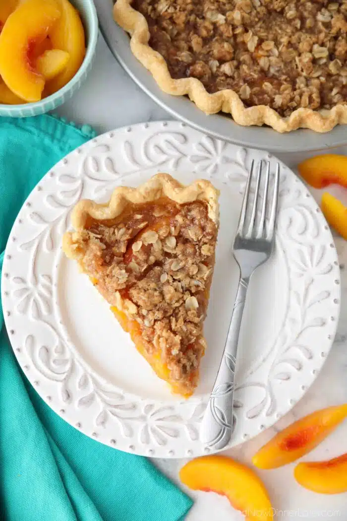 Top view of peach crumble pie on a plate with a fork.