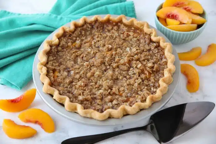 Fully baked peach crumble pie in pan.