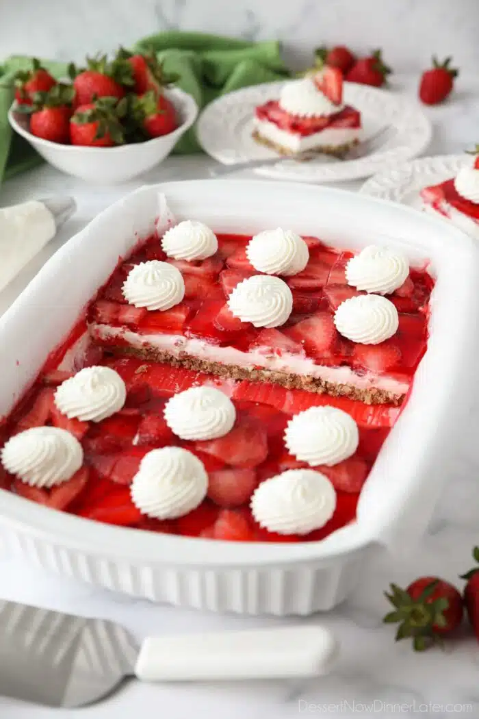 9x13-inch pan of strawberry pretzel salad with whipped cream swirled on top of each slice.