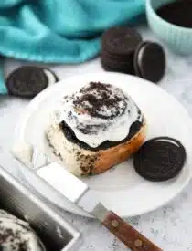 Top view of an Oreo cinnamon roll with cream cheese frosting on a plate.