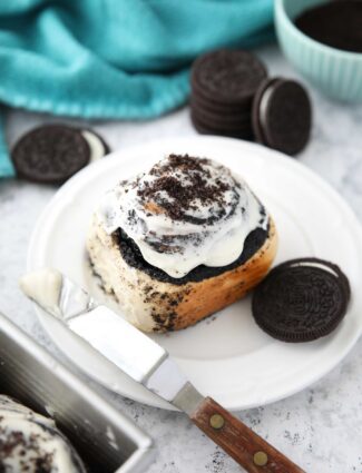 Top view of an Oreo cinnamon roll with cream cheese frosting on a plate.