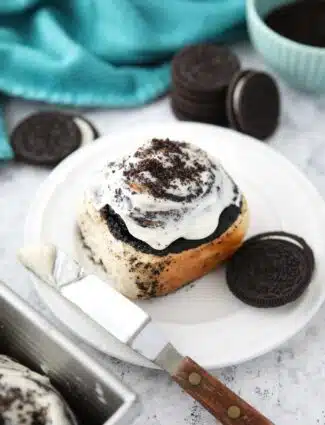 Top view of an Oreo cinnamon roll with cream cheese frosting on a plate.